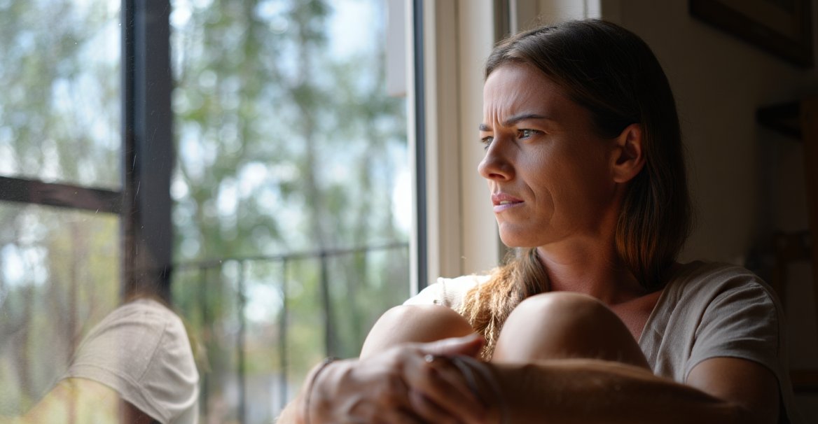 Девушка сидит на подоконнике и смотри в окно
